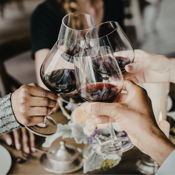 four red wine glasses clinking together